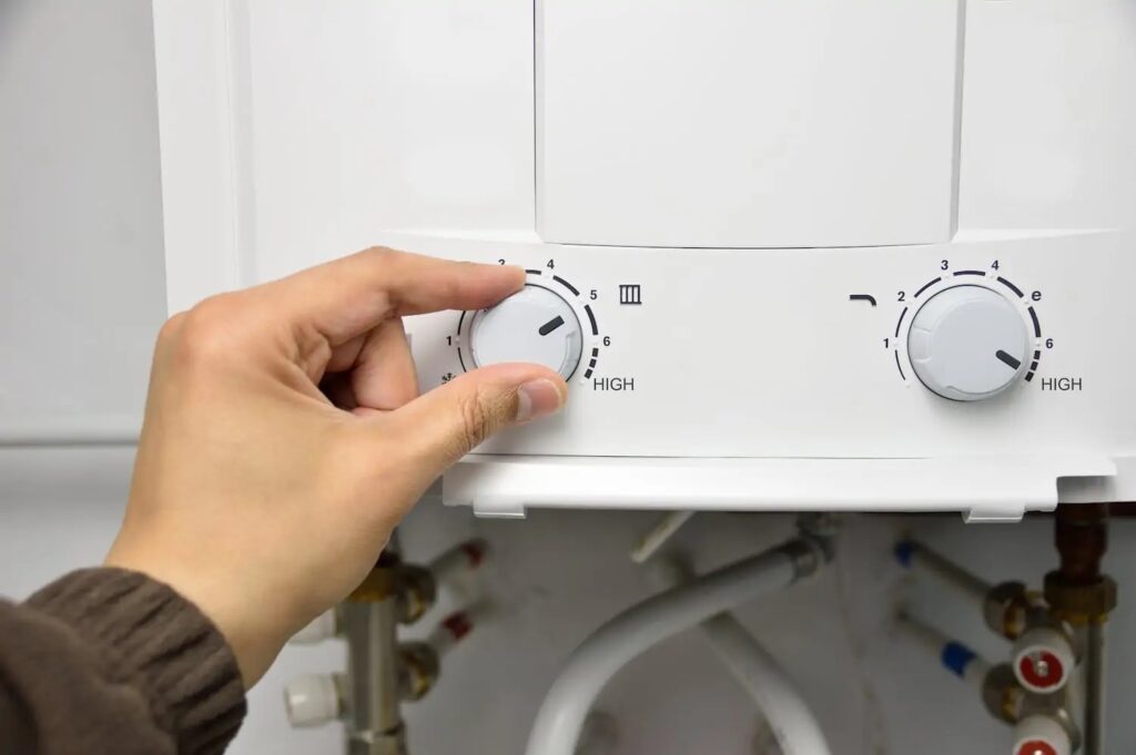 Person adjusting the settings on a tankless water heater
