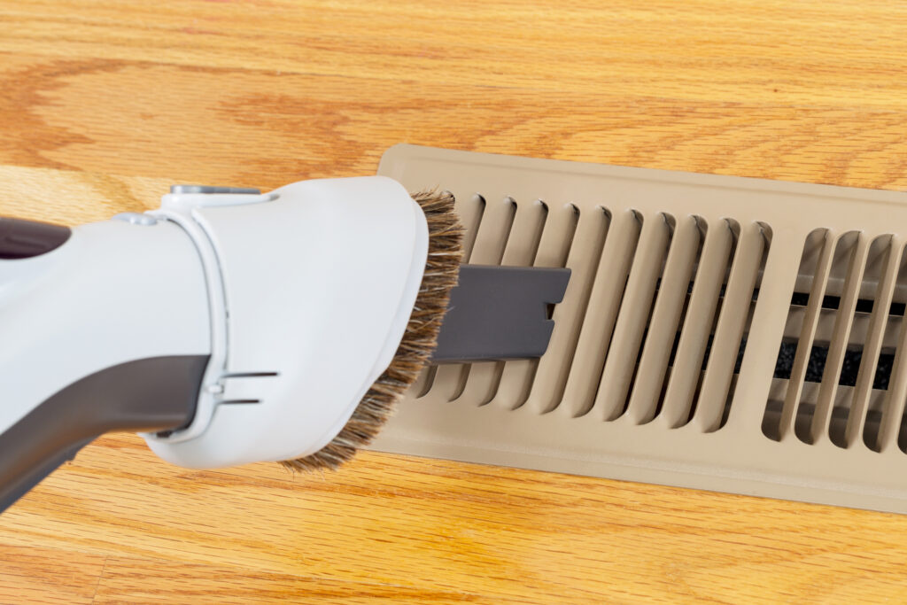 Vacuuming floor heater vent to prepare furnace before winter