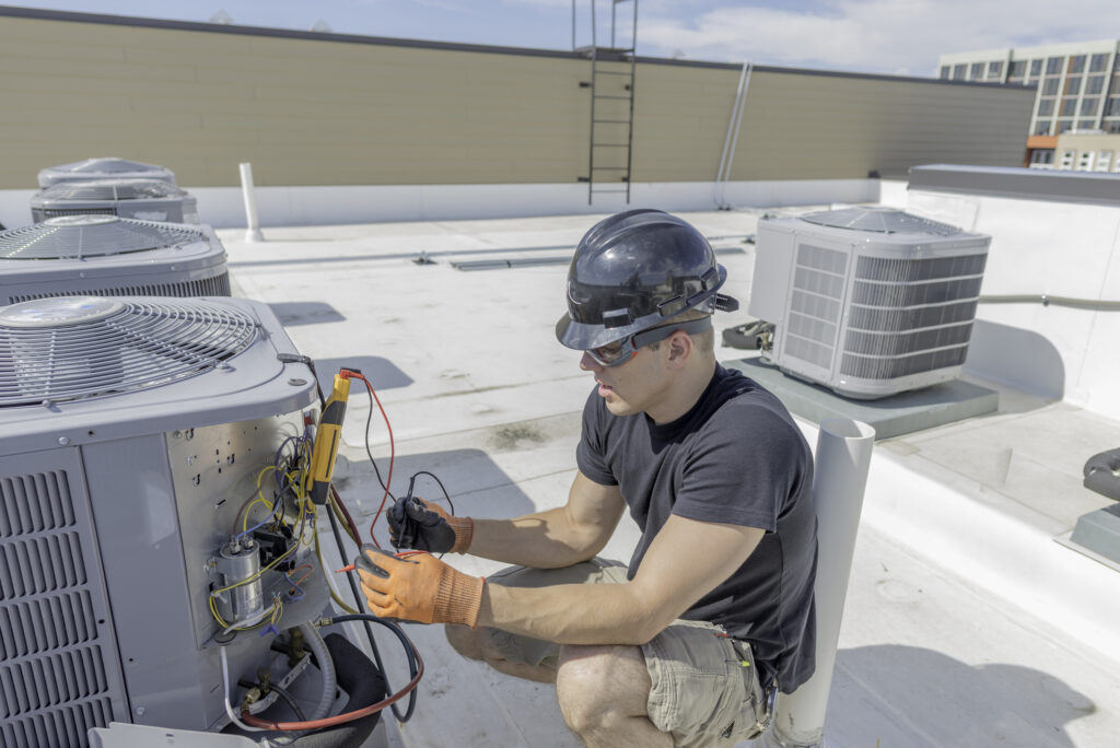 Commercial HVAC technician working on condenser unit on a rooftop HVAC unit