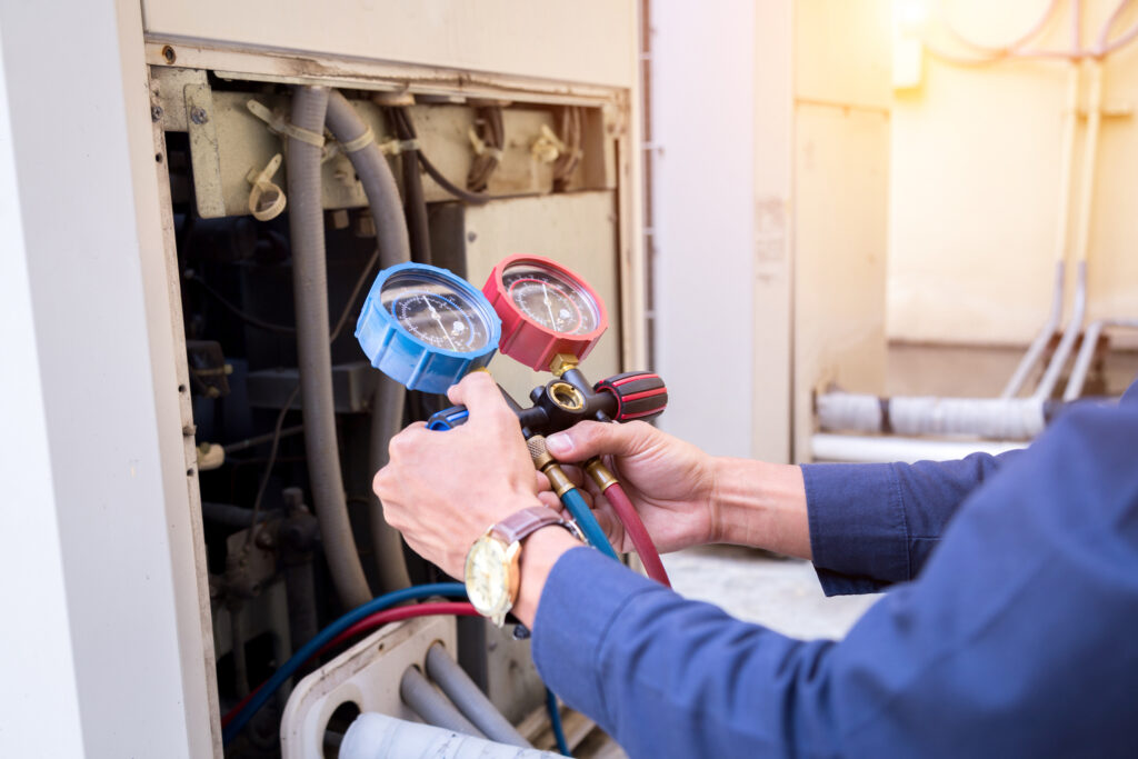 Commercial HVAC technician using gauges to check refrigerant pressure