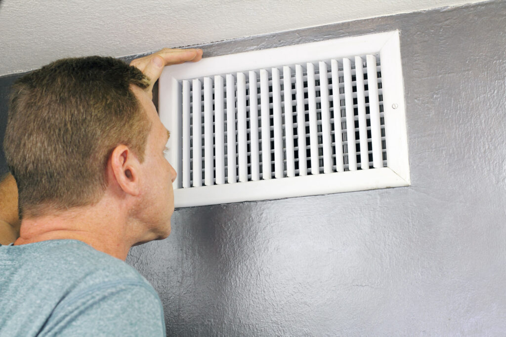 Homeowner looking at vent blowing warm air